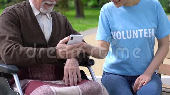 女志愿者教坐轮椅的老人如何使用手机视频的预览图