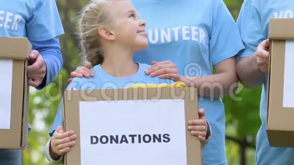 成人志愿者团队带着孩子拿着捐款箱微笑着慈善视频的预览图