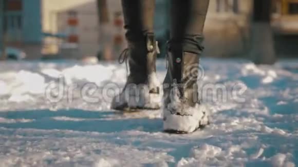 女足穿黑色靴子冬天走在雪地里在冬季公园散步的女人的腿视频的预览图
