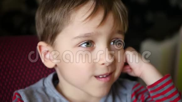 那个男孩望着远处微笑着把他的手放在耳朵后面快乐的孩子表现出快乐的情绪视频的预览图