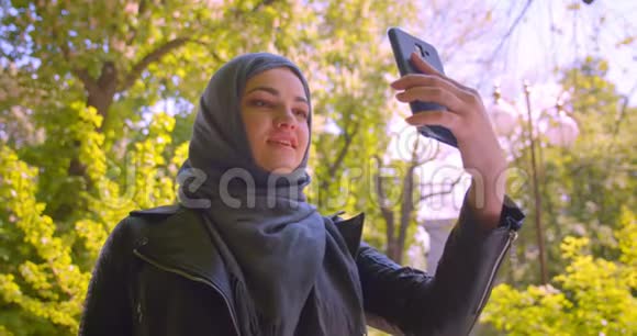 在公园里一位年轻漂亮的穆斯林女性戴着头巾在电话里打着视频开心地很开心视频的预览图