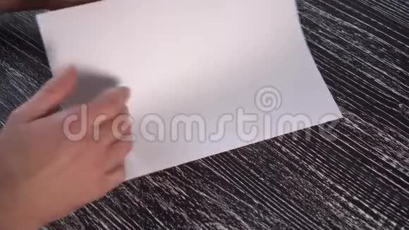 一个人用一张白纸在一张黑色的木桌上依次制造一架飞机视频的预览图