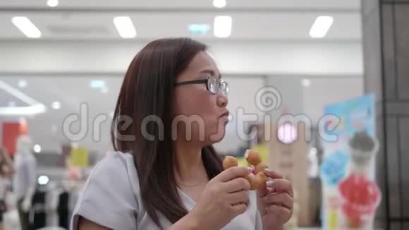 戴眼镜的女人坐在咖啡馆里吃甜甜圈视频的预览图