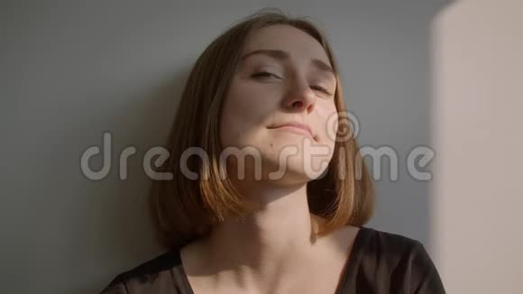 年轻的白种人女性坐在地板上微笑着开心地看着诱人的室内环境视频的预览图
