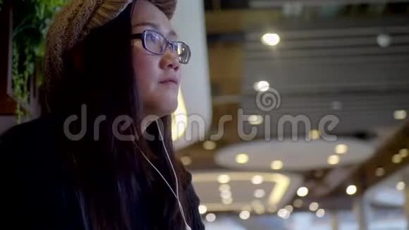 亚洲女人在商场里通过耳机听音乐视频的预览图