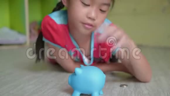 亚洲女孩把钱币放进储蓄罐里视频的预览图