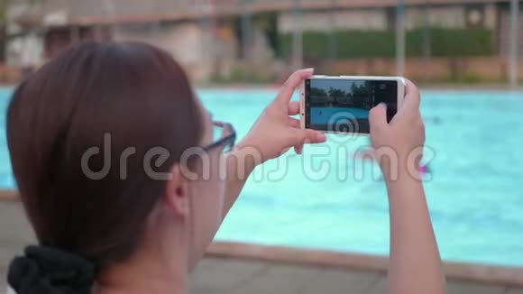 女士通过智能手机拍摄度假游泳池视频的预览图