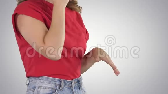穿着红色t恤的女人在梯度背景下打电话时做手势视频的预览图