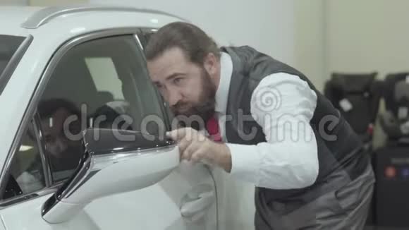 一位穿着商务套装的漂亮可爱自信留胡子的商人正在检查新买的汽车视频的预览图