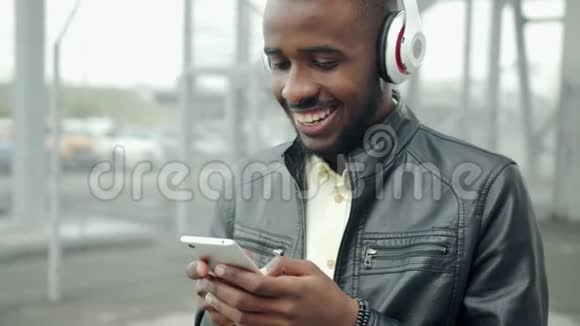 非洲裔美国学生耳机触摸户外智能手机屏幕视频的预览图