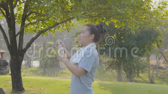 健身亚洲妇女在城市公园跑步后从瓶子里喝水视频的预览图