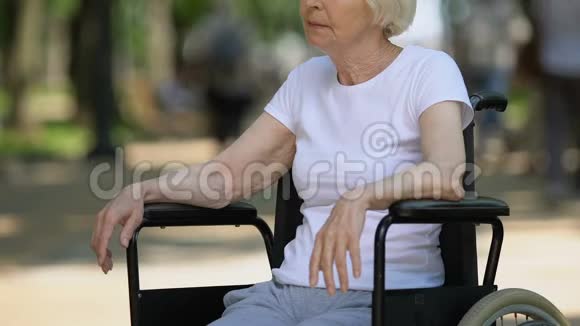 坐在公园里看人的坐在轮椅上的悲伤老年妇女残疾视频的预览图