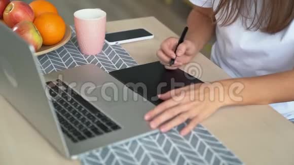 特写女设计师用手在带笔记本电脑的平板电脑上画画慢动作视频的预览图