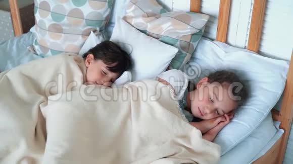 两个可爱的小女孩躺在床上睡觉休息慢动作视频的预览图