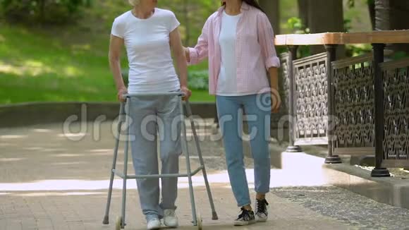 孙女用步行架支撑祖母在公园放松视频的预览图