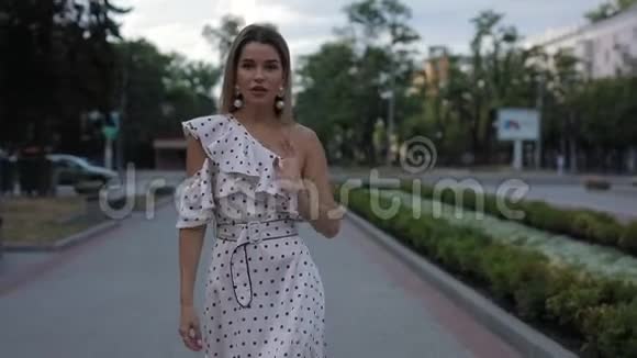 美丽优雅的女人穿着裙子在夏城小巷散步慢动作视频的预览图