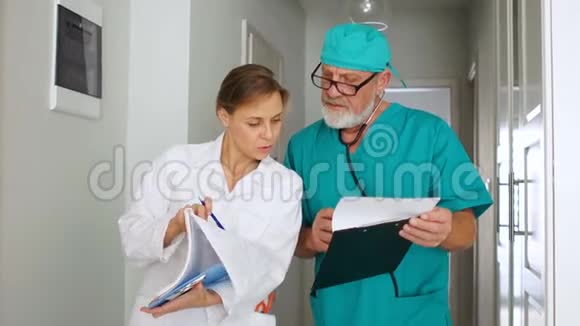 穿着医疗服的男医生和女医生在诊所走廊讨论病人检验结果视频的预览图