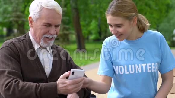 好心的女性志愿者帮助轮椅上的退休者使用智能手机慈善应用程序视频的预览图