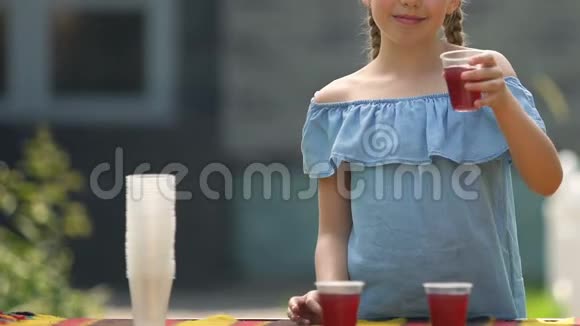 快乐女孩展示果汁塑料杯在户外卖提神糖浆饮料视频的预览图