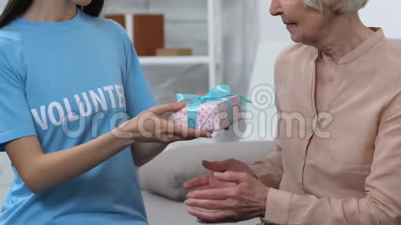 善良的女士志愿者为快乐的老妇人送礼物盒小惊喜视频的预览图