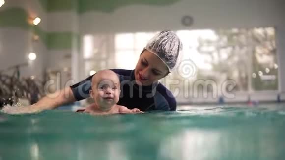 女教练或妈妈教一个小托德勒在水下潜水把他抱在水面上把他的头拧下来视频的预览图