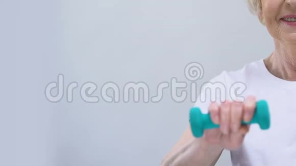 微笑的老年妇女在镜头前展示哑铃健身文字模板视频的预览图