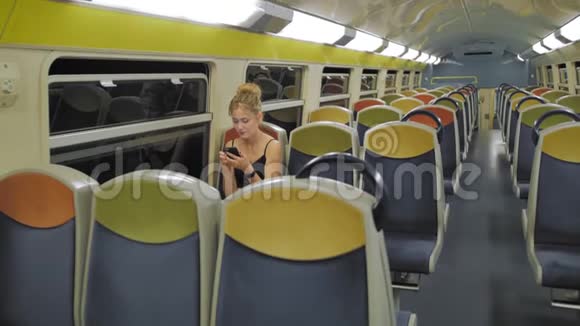 美丽的白种人女游客乘坐空的两级火车穿过黑暗的隧道在空排的后面视频的预览图