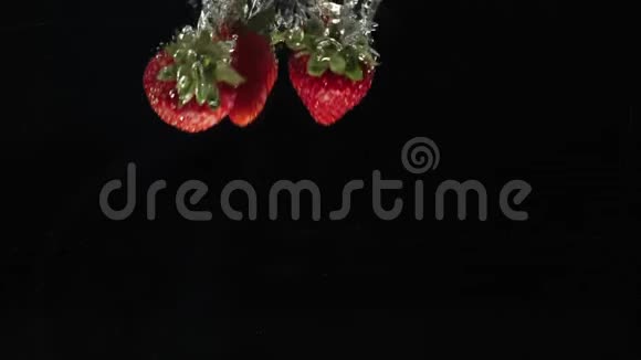 新鲜健康食品红色草莓在黑色背景下掉进水中新鲜水果溅在水族馆里有机浆果视频的预览图