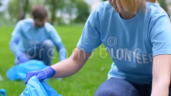 年轻的女志愿者在公园里捡垃圾相机微笑拯救自然视频的预览图