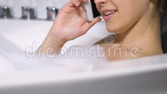 漂亮的年轻女人在浴室里打电话愉快的谈话闲话视频的预览图