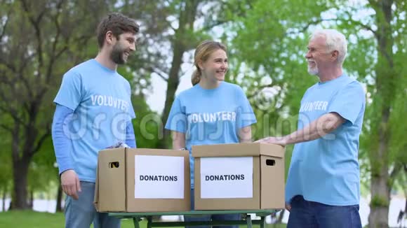 快乐的志愿者奉献高五捐赠箱在桌上慈善活动视频的预览图