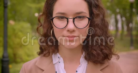一位年轻的长头发的白种人卷曲的女学生戴着眼镜笑着愉快地看着视频的预览图