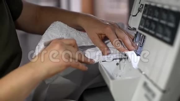 女性裁剪的双手缝制白色婚纱在超锁机上工作做边缘加强纺织边缘视频的预览图