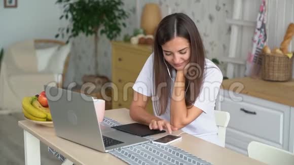 女孩在笔记本电脑工作之间休息用耳机听音乐跳舞慢动作视频的预览图