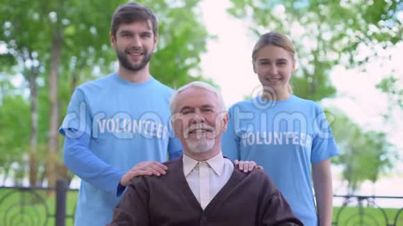 两名社会活动家和年长男性在镜头前微笑照顾老人视频的预览图