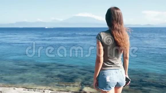 站在岸上的女孩向大海挥手缓慢的动作视频的预览图