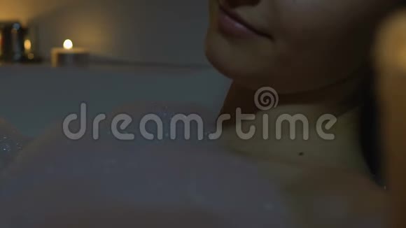女人在浴室里用泡沫和芳香蜡烛放松晚上的水疗仪式视频的预览图