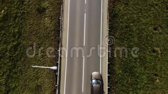 鸟瞰孤独的棕色SUV汽车在两片田野之间的道路上行驶两条车道的路上有车视频的预览图