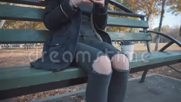 公园里坐在长凳上吃汉堡的女孩穿着夹克和帽子的女孩视频的预览图