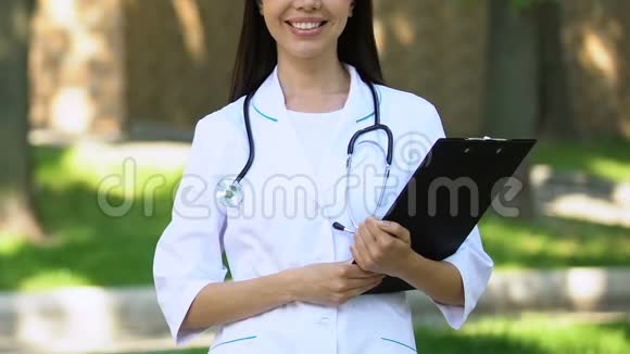 高度合格的医生有文件夹和听诊器站在室外微笑视频的预览图
