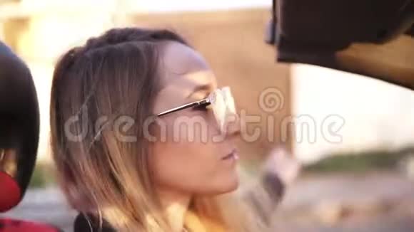 戴着透明太阳镜的长头发女孩无忧无虑地驾驶着她在城里开的敞篷车年轻体贴的女人视频的预览图