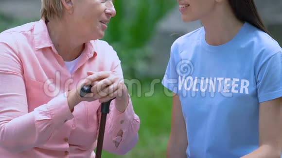 微笑的志愿者在公园里用手杖和年长的女人聊天视频的预览图