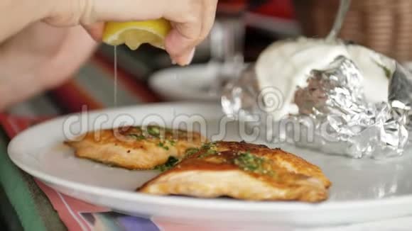 女人吃红烤鲑鱼和土豆女孩用柠檬汁和盐浇鱼高蛋白食物视频的预览图