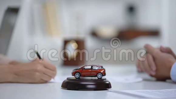 桌上的汽车玩具妇女在背景下签署车辆购买或保险视频的预览图