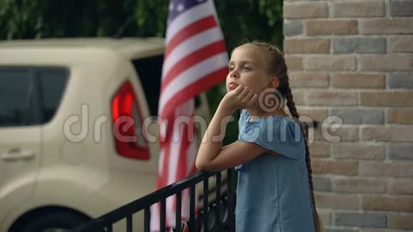 无聊的小女孩在房子的露台上等着阳光明媚的天气接雨滴视频的预览图
