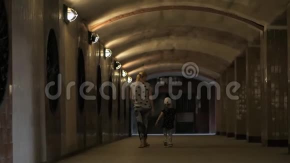 一个女人和一个小女孩牵着手穿过隧道视频的预览图