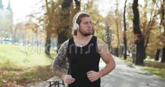 体育理念马拉松运动员穿耳机和听音乐的锻炼他在公园里慢跑视频的预览图
