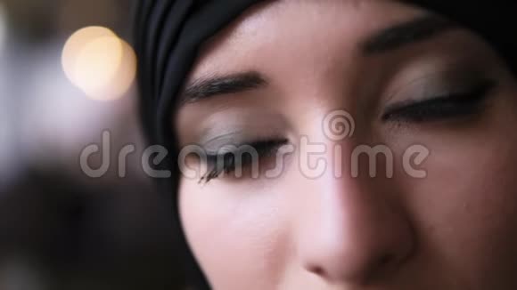 一位身穿黑色头巾的中东穆斯林年轻女子的极端特写镜头她睁开深棕色的眼睛看着镜头视频的预览图