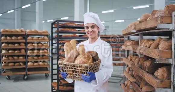 微笑着一个有魅力的成熟面包师女士拿着一个带有有机面包的老式篮子直视着他视频的预览图