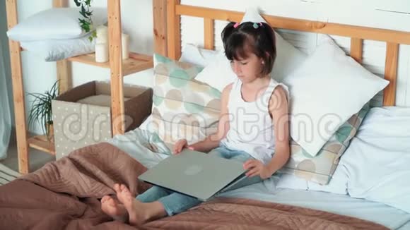 女孩坐在床上打开笔记本电脑情绪上说些什么慢动作视频的预览图